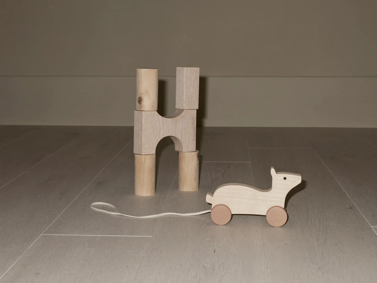 Cubes en bois naturel et animal à tirer sur un parquet clair