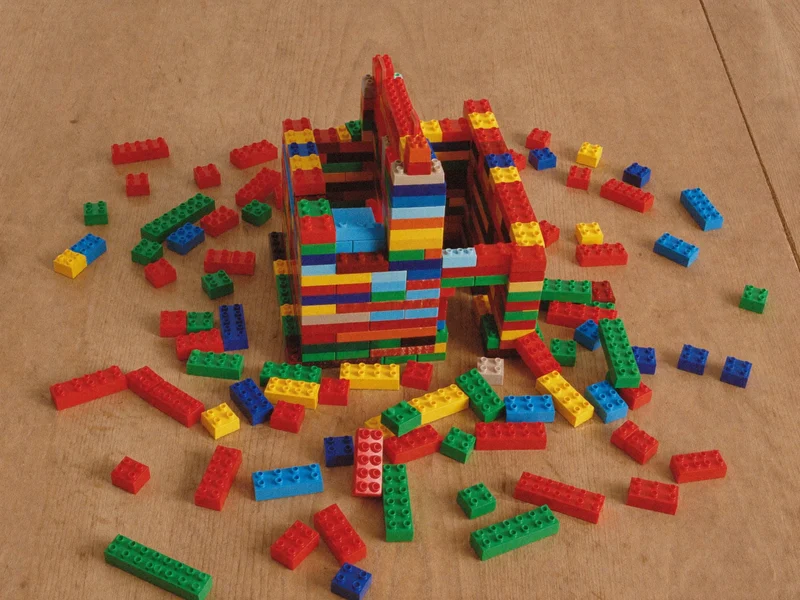 Briques colorées à emboîter et petite maison à moitié construite sur une table